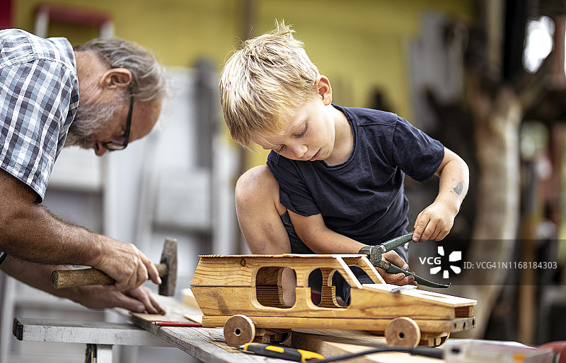 爷爷和孙子用木头做汽车图片素材