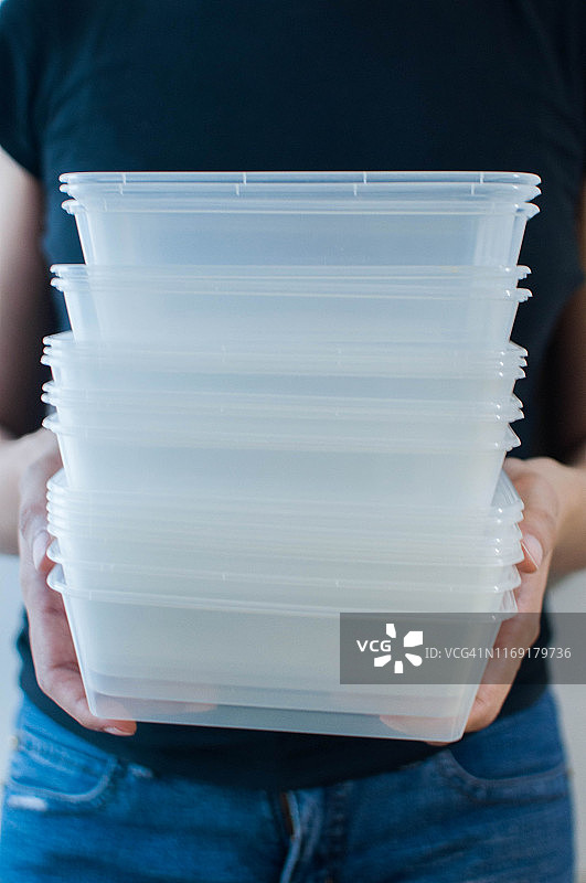 一名年轻女子正拿着一个白色背景上的可回收塑料食物容器图片素材