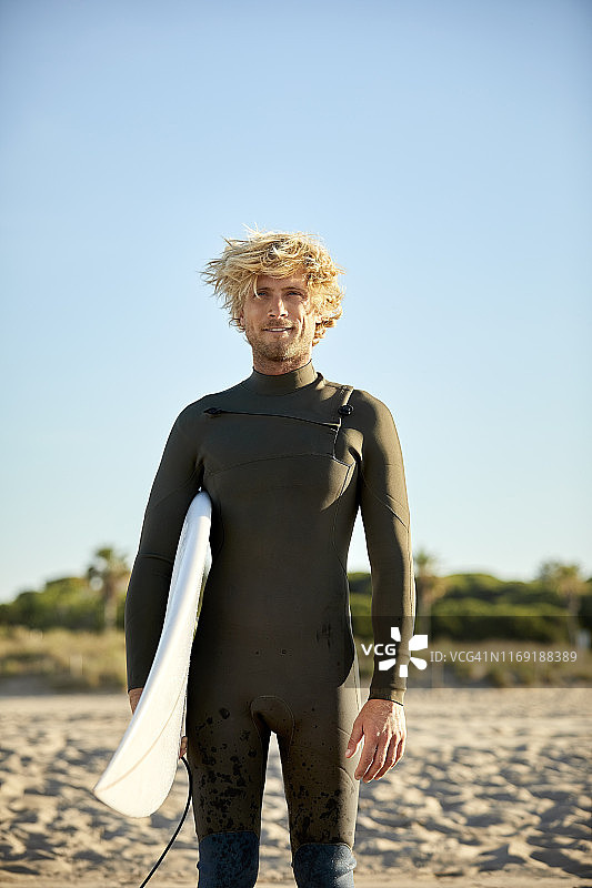 在海滩上背着冲浪板的自信男子图片素材