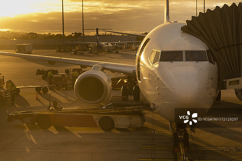日落时分，一架商用飞机停在停机坪上图片素材
