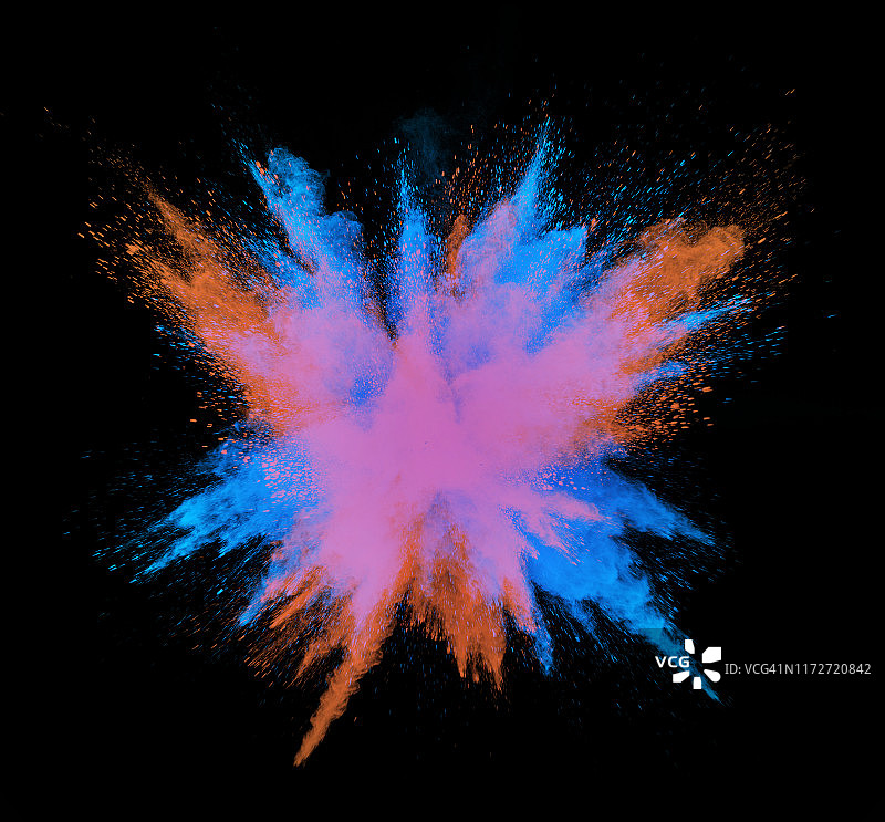 在黑色的背景上，一团粉红色和蓝色的粉末颗粒撞击爆炸。图片素材