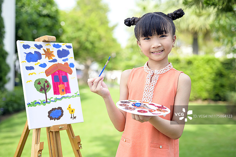 一个有才华的小女孩在公园的帆布上画画。图片素材