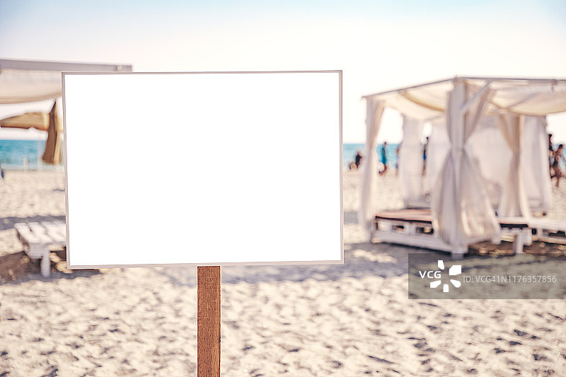 空海滩广告牌模拟。为你的文本或图像复制空间。白色的沙子，蓝色的大海和背景中的人们。图片素材