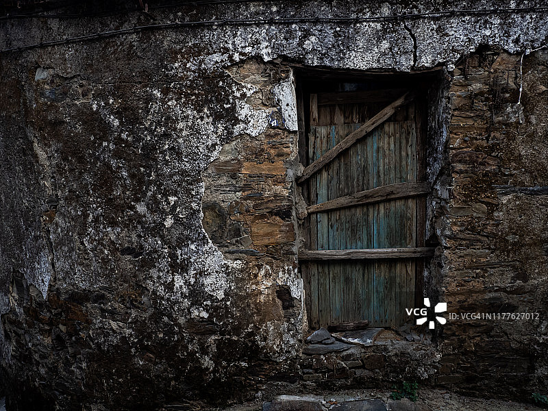 在Las Hurdes的一个被遗弃的中世纪城镇的一个被遗弃的房子的入口，狭窄的街道和被遗弃的用石头和石板建造的房子，木制的门和窗户和被毁坏的房子。农村人口减少的概念图片素材