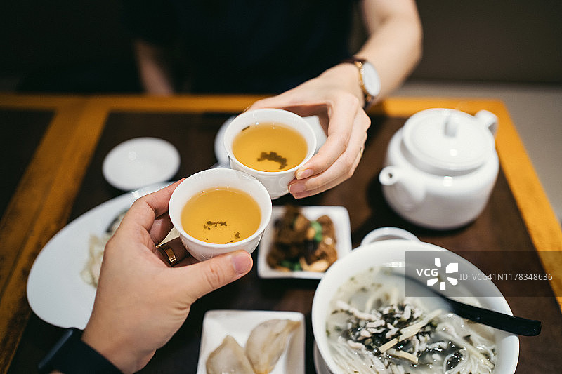 在中国餐馆用餐时，男女握手敬茶图片素材