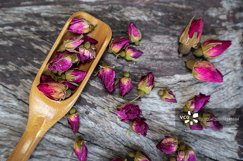 玫瑰茶背景，大马士革玫瑰花蕾，整体健康茶，茶由茶玫瑰花瓣在一个玻璃杯在木制背景图片素材