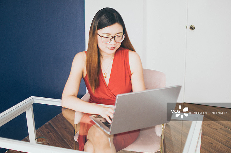 一位年轻美丽的亚洲女子正在办公室里使用笔记本电脑图片素材