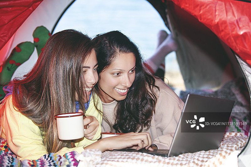 两个年轻的女人在帐篷里面对着笔记本电脑图片素材