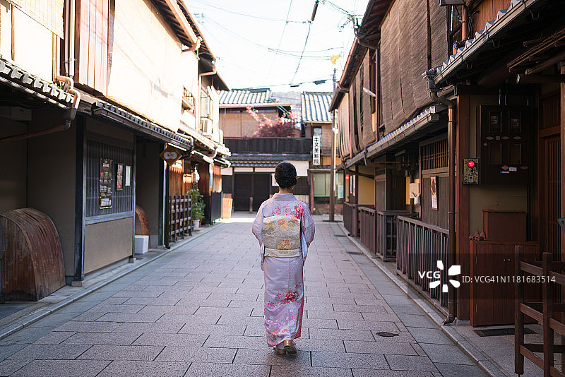 年轻的亚洲女士穿着和服走在东山区，园，日本京都，空旷的街道上图片素材