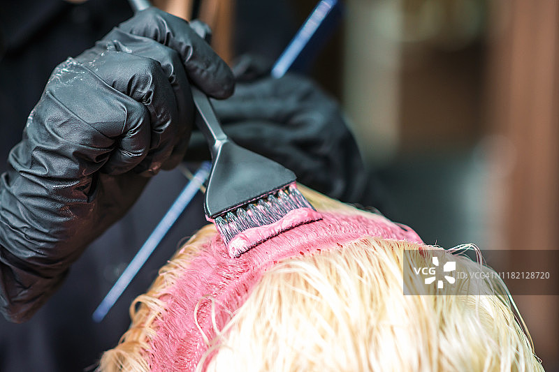 理发师正在把顾客的白发染成粉红色。图片素材