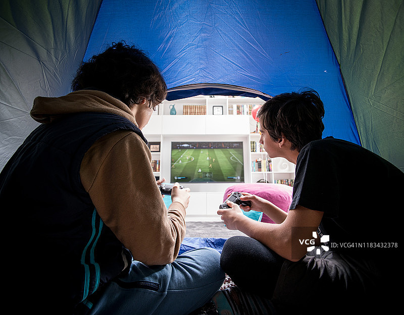 男孩们坐在帐篷里玩电子游戏图片素材