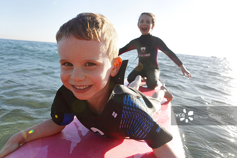 两个孩子在海里玩冲浪板图片素材