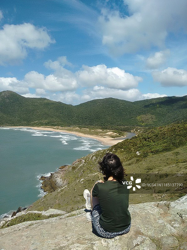 在巴西圣卡塔琳娜州Florianópolis，女孩坐在未被开发的拉古尼亚海滩附近图片素材
