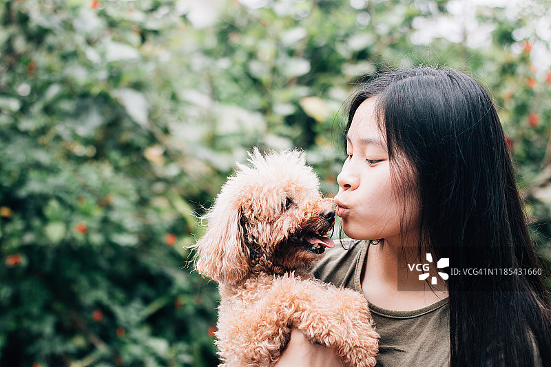 亚洲青少年女性亲吻贵宾宠物狗的特写图片素材
