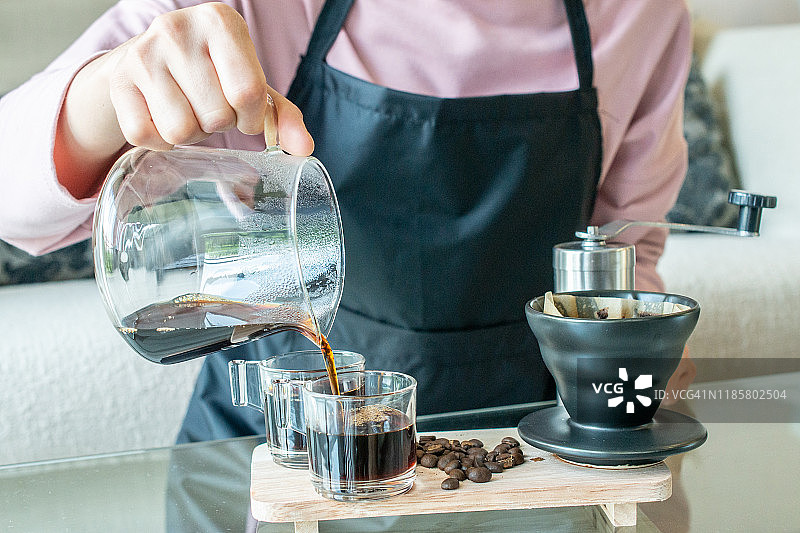 镜头镜头的咖啡师倒热水在磨碎的咖啡与纸过滤器，使一滴咖啡。图片素材