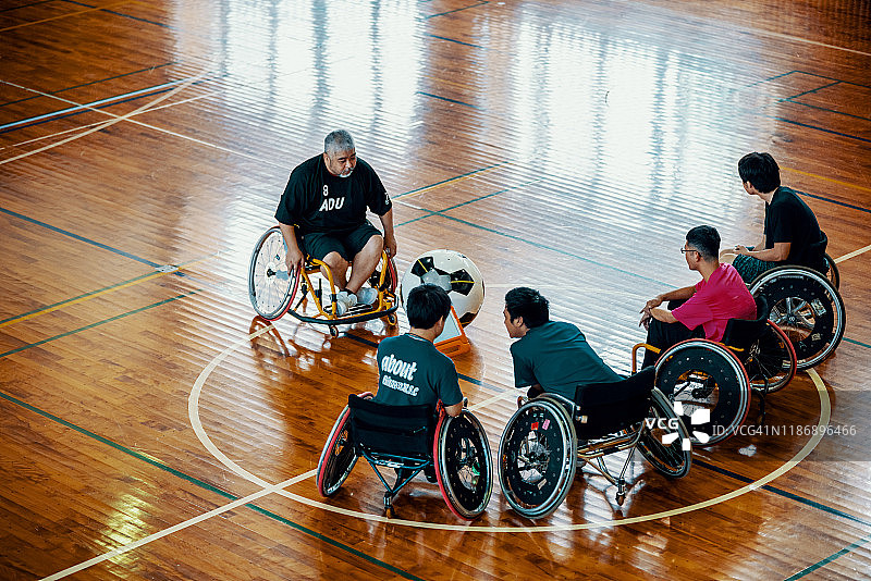 教练在体育馆和轮椅足球队的队员聊天。图片素材