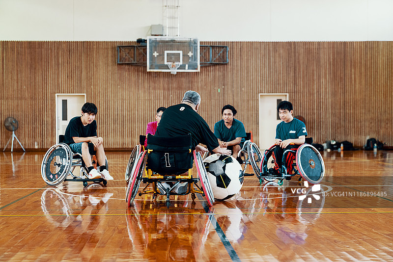 教练在体育馆和轮椅足球队的队员聊天。图片素材