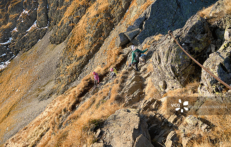 一群女孩爬上Negoiu峰，这是位于欧洲罗马尼亚喀尔巴阡山脉法加拉斯山脉的一条特别危险的线路。图片素材