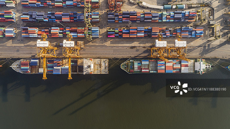 码头商埠集装箱货轮高空俯视图，工作起重机桥装集装箱，用于商业物流、进出口、运输。图片素材