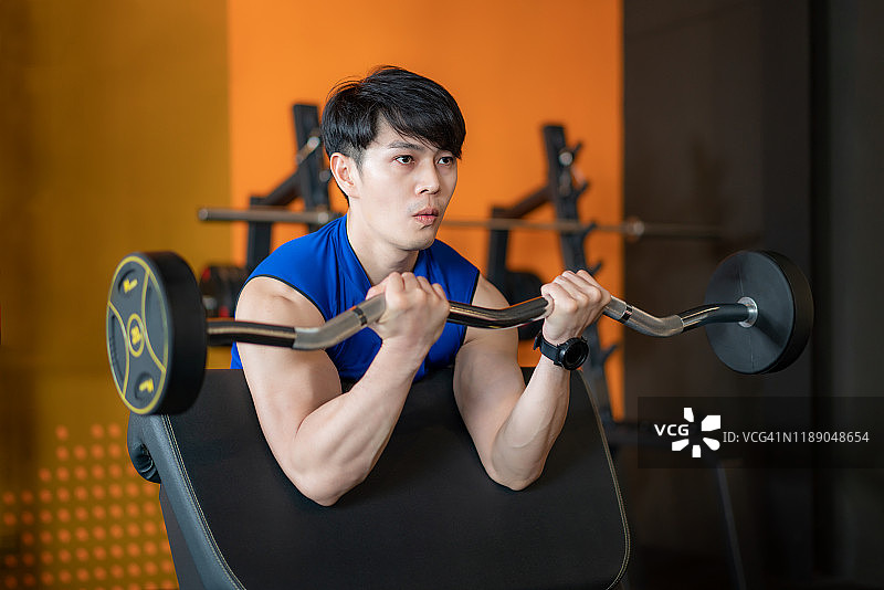 亚洲的肖像有吸引力的年轻男子坐在健身房的重量棒。健身，运动，训练，健身房和生活的概念。图片素材