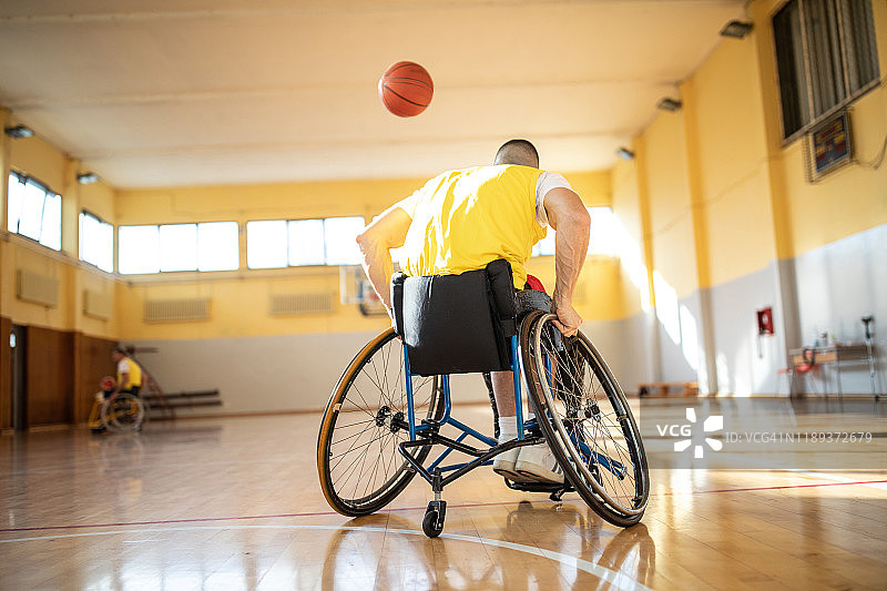 残疾人坐在轮椅上和他的朋友在篮球场上打篮球图片素材