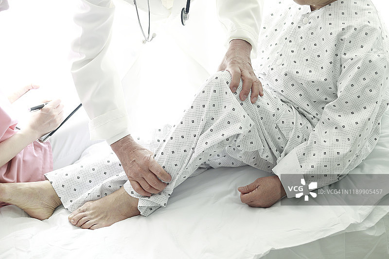 医生在病床上检查老病人的腿图片素材