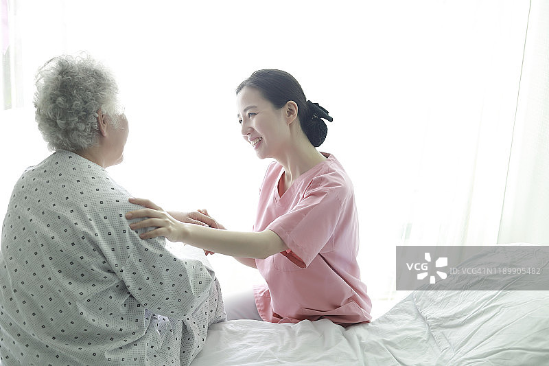 护士在病床上帮助一位老妇人图片素材
