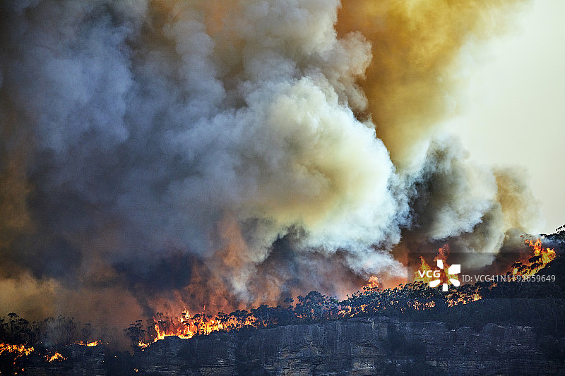 在澳大利亚蓝山的山脊上，森林大火，火焰和太阳照亮了烟雾的薄暮图片素材