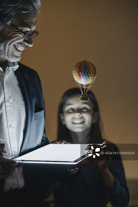 快乐的高级商人和女孩在办公室里拿着热气球和闪亮的平板电脑图片素材