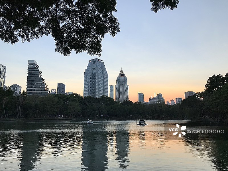 一个湖与夕阳背景下的曼谷摩天大楼从伦皮尼公园图片素材
