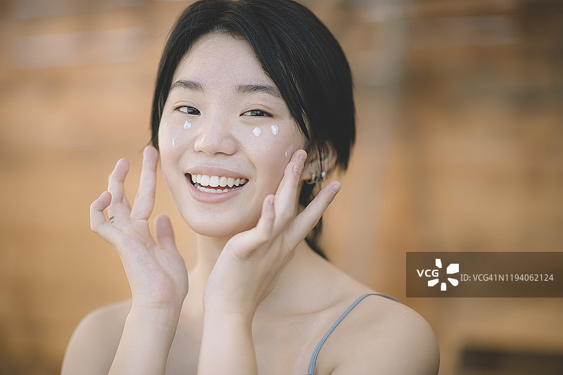一位亚洲华裔少女在户外涂抹护肤霜图片素材