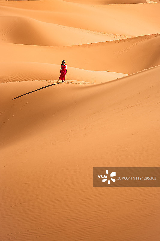 年轻女子走在美丽的沙丘上撒哈拉沙漠，摩洛哥，非洲图片素材