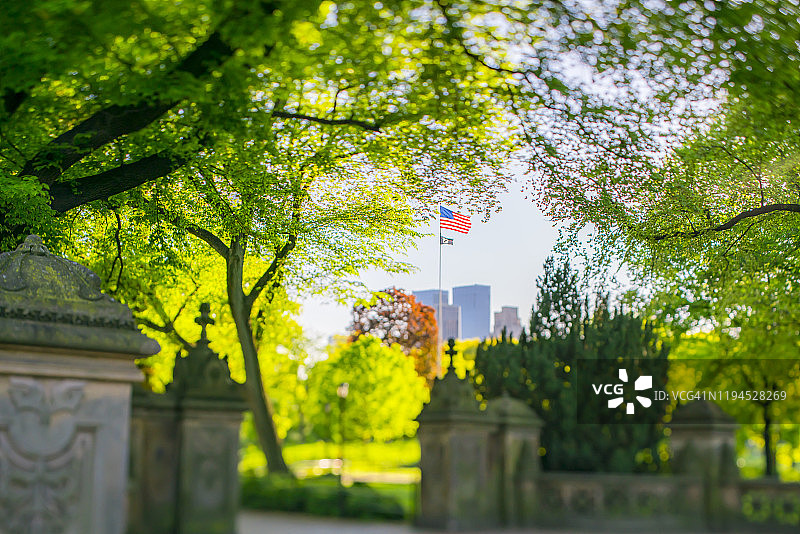 许多正在生长的新鲜的绿叶树围绕着美国国旗在石头大门墙在纽约中央公园在美国纽约5月08日图片素材
