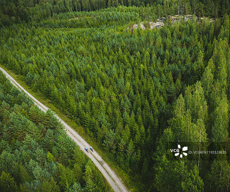 鸟瞰图两个骑自行车的人在一个小泥土路在芬兰的森林中间图片素材