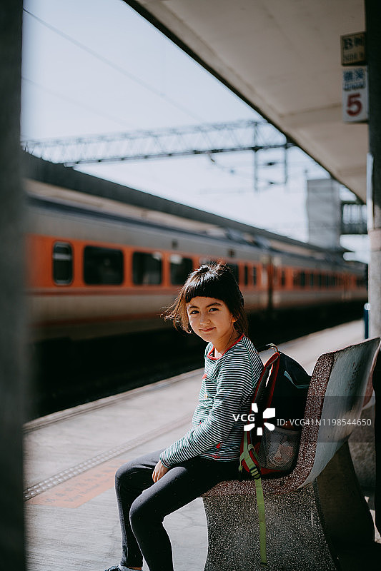 台湾，可爱的欧亚姑娘坐在火车站月台的长凳上图片素材