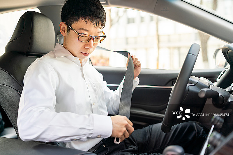 年轻的亚洲男子在开车前系安全带图片素材
