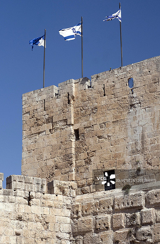 低角度的以色列国旗飘扬在以色列耶路撒冷的一堵历史悠久的墙上图片素材