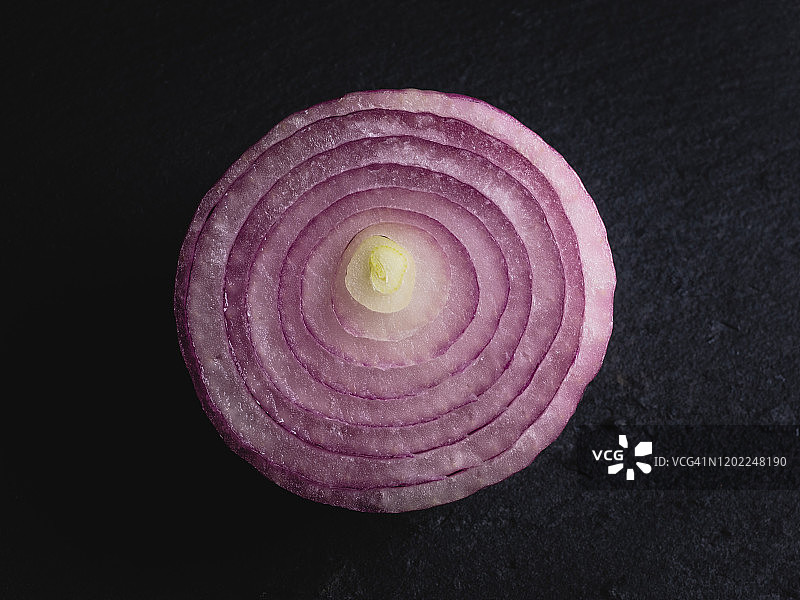 俯视图的一半紫色的洋葱在黑暗的背景。图片素材