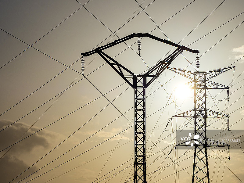 大的高压电塔用于在日落时分配电力。图片素材