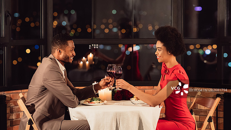 在全景餐厅的浪漫晚餐中，幸福的夫妻互相碰杯图片素材
