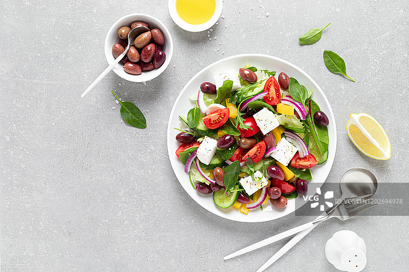 白色盘子上的希腊沙拉，绿色蔬菜，橄榄和羊乳酪，俯视图图片素材