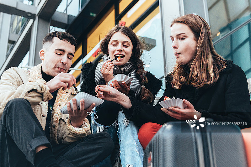 三个年轻人在柏林户外吃咖喱香肠图片素材
