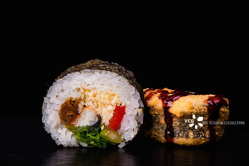 传统的新鲜日本寿司卷在黑色的背景。油炸寿司。图片素材