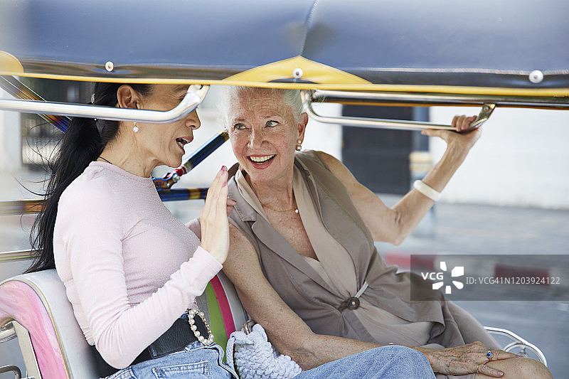 一个女人在嘟嘟车里和一个微笑的女人聊天图片素材