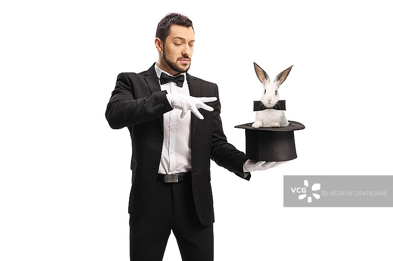 年轻的男魔术师用一只戴着大礼帽的兔子做魔术图片素材