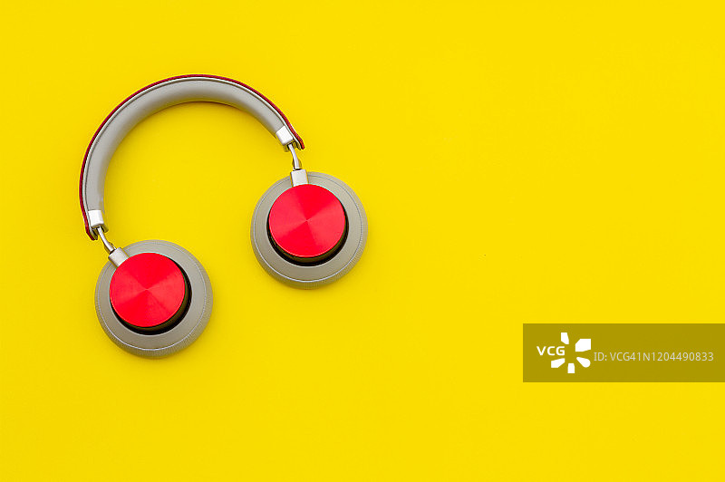 黄色背景上的红色耳机。音乐的概念。图片素材