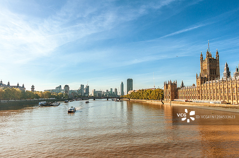 背景是英国议会大厦、泰晤士河和摩天大楼，映衬着晴朗的蓝天图片素材