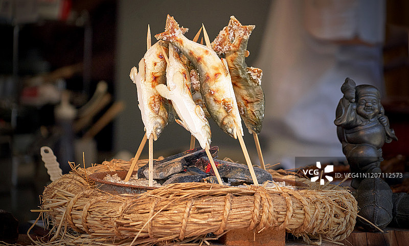 鱼串在棍子上，用传统的日本方式在火炭上烤着，象征着日本文化图片素材