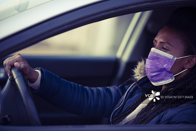 开车时戴着面罩的女人。图片素材