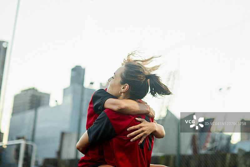 两名女子足球队队友在进球后拥抱庆祝。图片素材